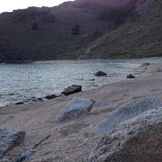 Coarse sand is punctuated by small rocks.