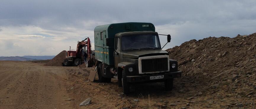 A truck and a digger on the side of the road.