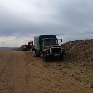 A truck and a digger on the side of the road.