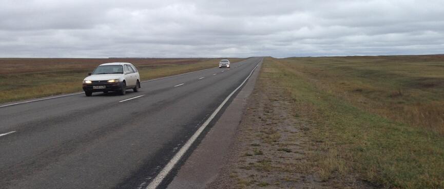 A narrow shoulder gives way to a strip of muddy grass.