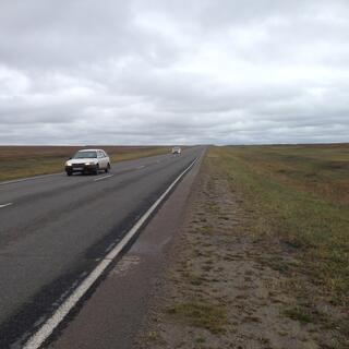 A narrow shoulder gives way to a strip of muddy grass.