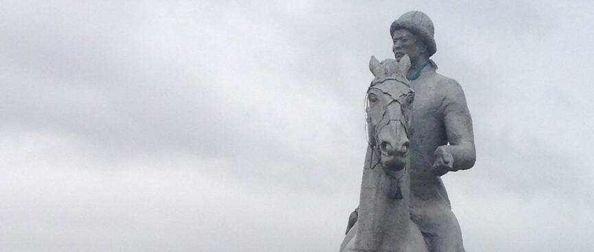 Ribbons adorn the legs of a concrete horse ridden by a concrete man.