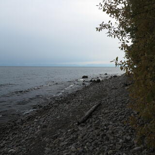 Small waves lap at the shoreline of a pebbled beach.