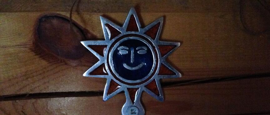 A metal coat hook adorned with a smiling sun.
