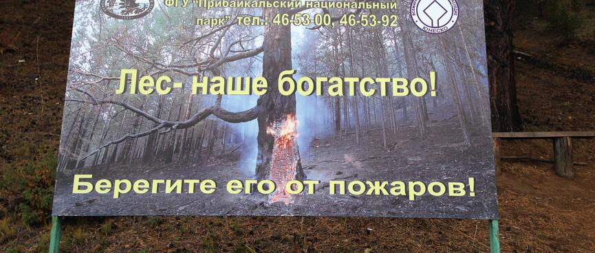 A printed signs shows a smouldering tree in a fire ravaged forest.