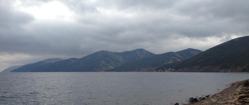 Grey clouds hang over blue-grey waters and a rocky coastline.