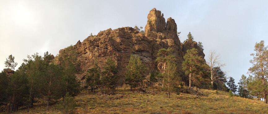 A jagged outcrop at the top of a grassy hill.