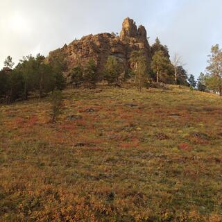 A jagged outcrop at the top of a grassy hill.