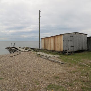 A small wooden jetty next to a boat house.