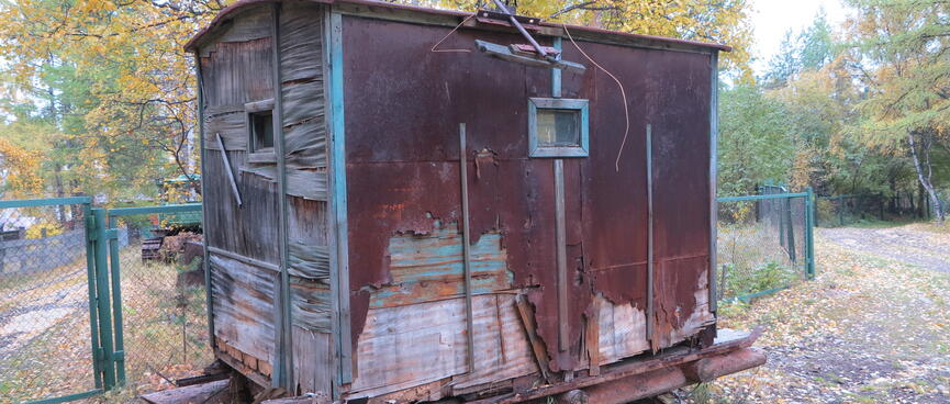 An small railway carriage sits on top of log skids.