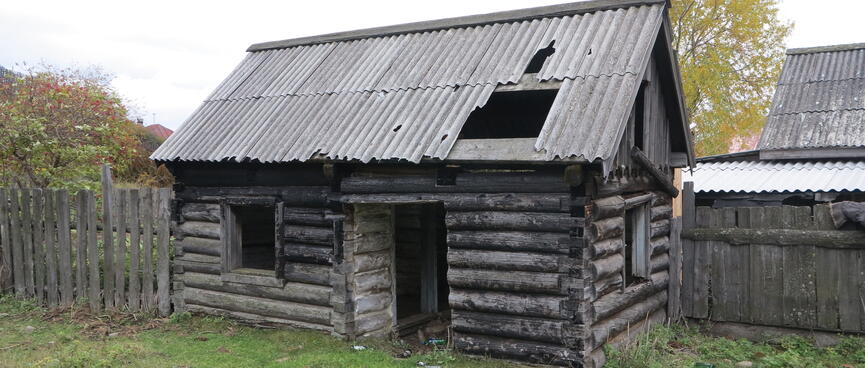 An abandoned house with a large hole in the roof.