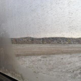 Hills and snow covered ground seen through a dirt spattered window.