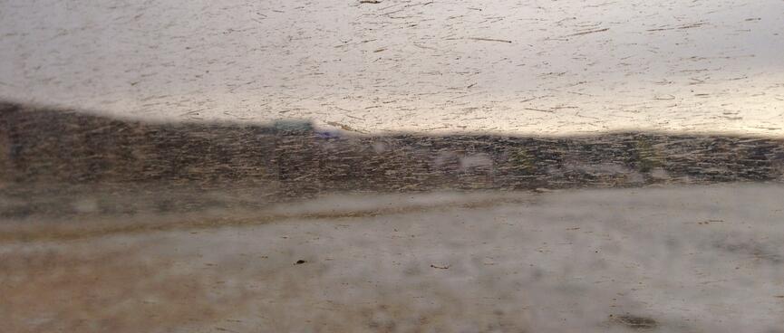 Hills and snow covered ground seen through a dirt spattered window.