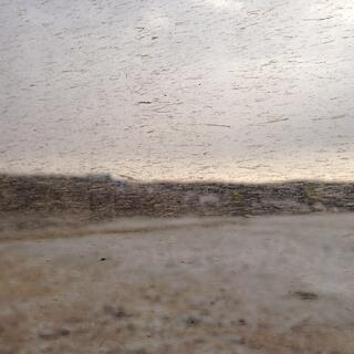 Hills and snow covered ground seen through a dirt spattered window.