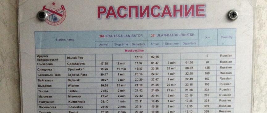 An rectangular sign titled 'РАСЛИСАНИЕ' (schedule) containing columns of places and times.