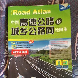 The soft cover of an atlas shows Chinese writing and pictures of empty highway.