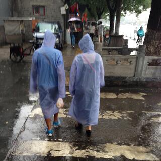 Two people wear see through raincoats to beat the downpour.