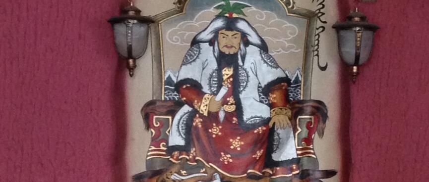 Chinggis Khan sits on a throne, dressed in furs and moccasins.