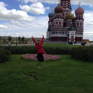 Mandy launches herself into the air, in front of a church with onion shaped domes.