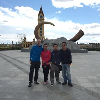 Our group of four poses in front of a mammoth tusk set in concrete.