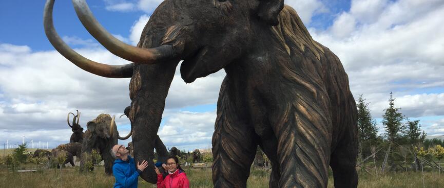 Mandy and I hold on to a mammothʼs long trunk.