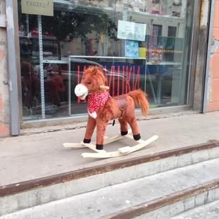 A brown rocking horse wears a red cowboy scarf.