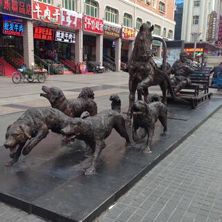 Bronze statues of four dogs and a horse, pulling the same man.