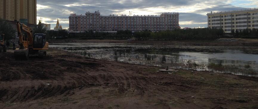 Large classical apartment blocks form a backdrop to muddy tyre tracks from two diggers.