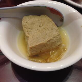 A porcelain spoon cradles a decent chunk of brown tofu.