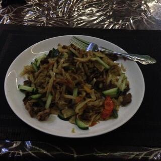 A plate of noodles, cucumber, tomato and meat.