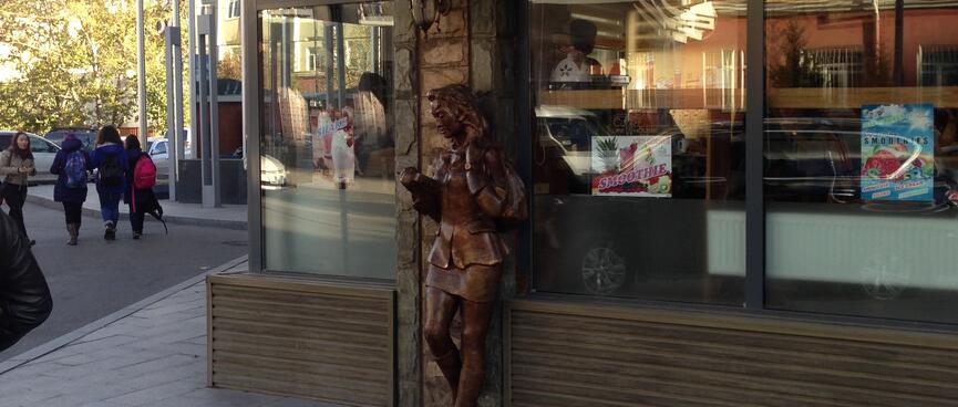 A bronze statue reads a book, outside the Uni Coffee House.