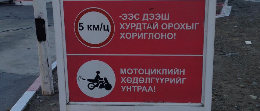 Sign at a petrol station depicts 5 km/h speed limit and a speeding motor scooter.
