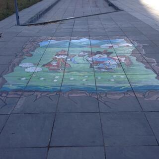 A chalk drawing on the footpath depicts women in traditional dress.