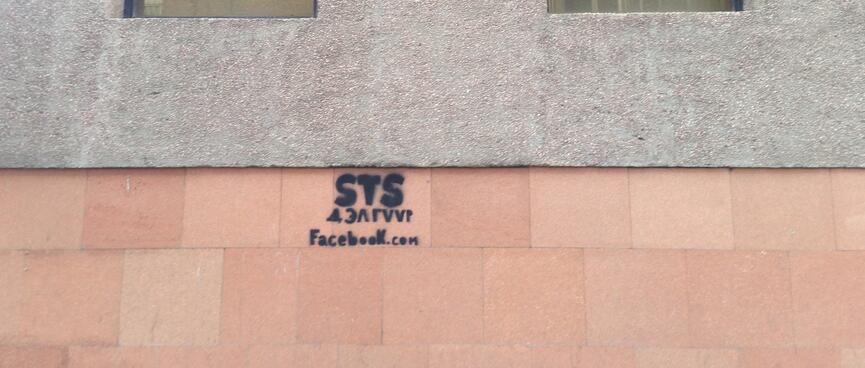 A website address spray painted on a building wall.