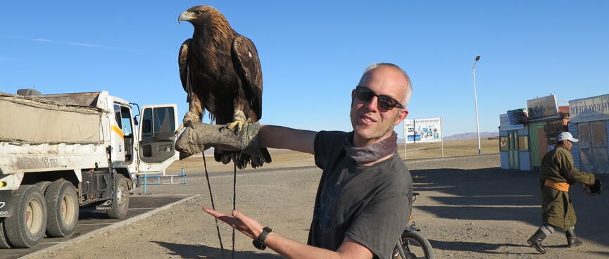 I look at the camera while an eagle perches on my forearm.