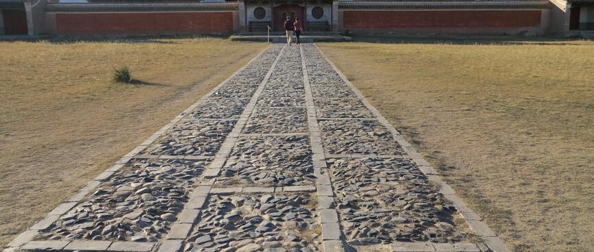 A long stone path leads to a walled area.