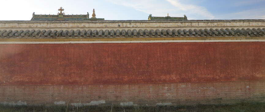 Rooftops are just visible over the top of a red wall.