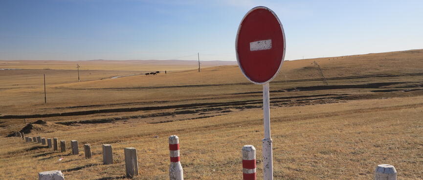 A No Entry sign and white fenceposts with red stripes.