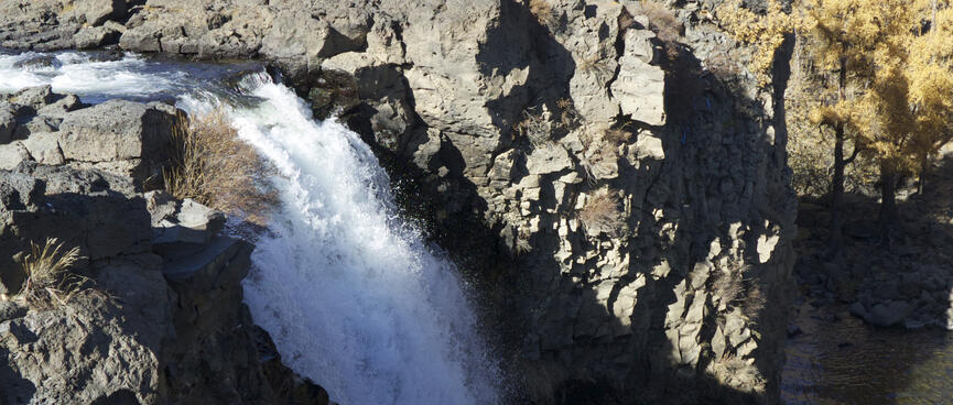 A foaming waterfall plunges down a rock face.