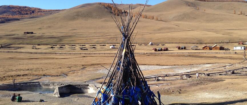A large teepee of branches is secured with blue ribbon.