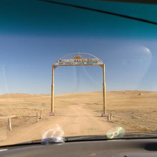 A simple wooden archway straddles a dirt road.