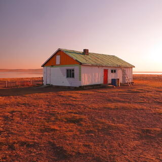 A white red and green house bathed in an orange glow.