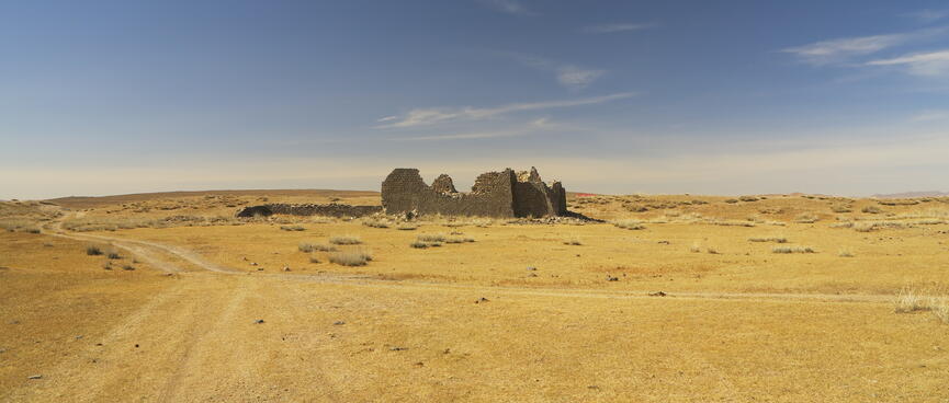 The empty desert landscape around the derelict stone walls.