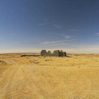 The empty desert landscape around the derelict stone walls.