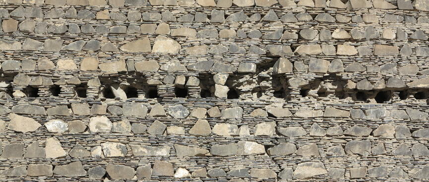A row of holes in the centre of a stone wall.