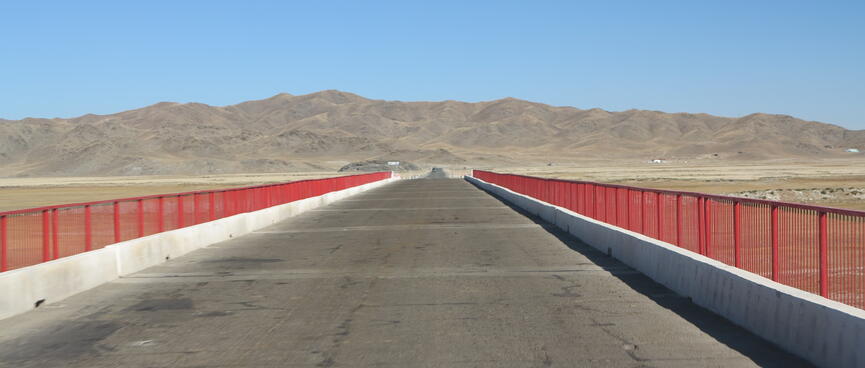 Red metal rails run along the sides of an asphalt road bridge.