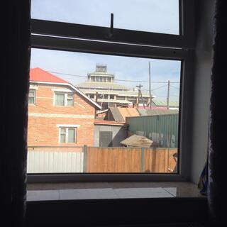 The view out of the window includes a tired two-storey house, half a shipping container and some low key construction.