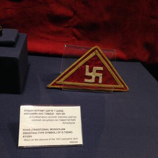 A sewn triangle badge with a gold swastika and border.