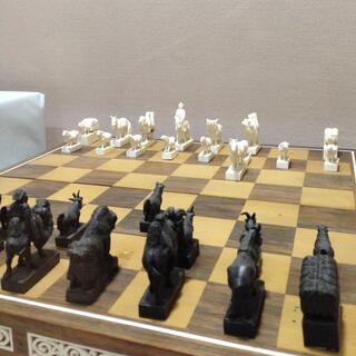 Black and white chess pieces in the shapes of sheep, horses, camels, goats and herders.