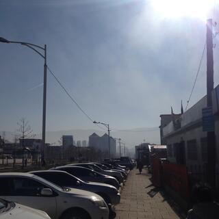 Sun and clear blue sky above a line of parked cars.